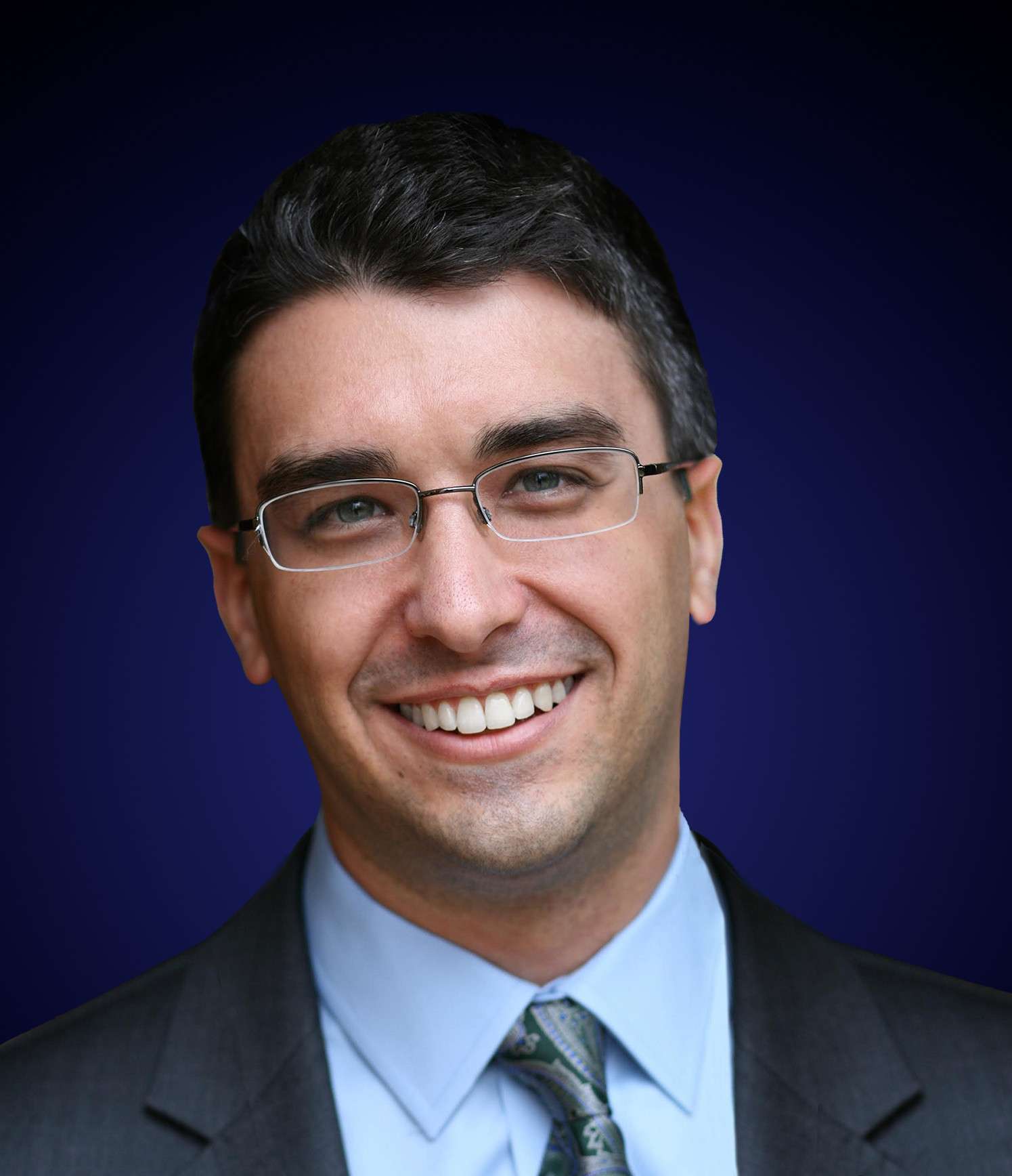 Business professional smiling in formal attire with glasses.