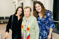 A warm family moment with mother and daughters at an indoor event.