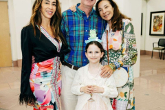 A joyful family gathering at an art gallery, featuring a man, two women, and a young girl dressed elegantly for a celebration.